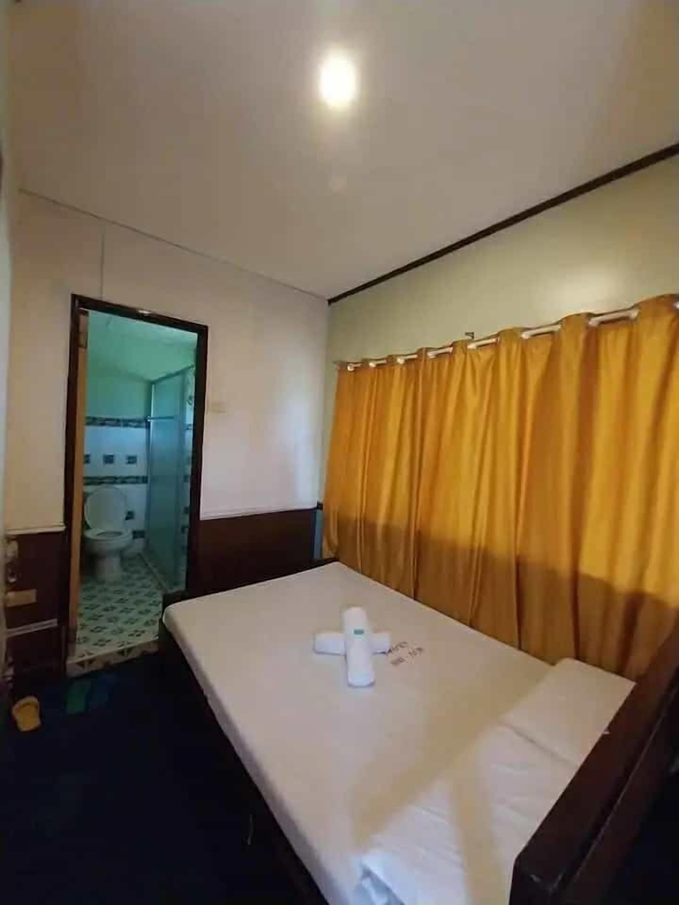 Une chambre d’hôtel avec un lit, une salle de bain visible à travers une porte ouverte et un rideau.