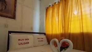 A hotel room with a neatly made bed, two pillows with text, and a decorative swan made of towels. - WJV INN LILOAN (Liloan)