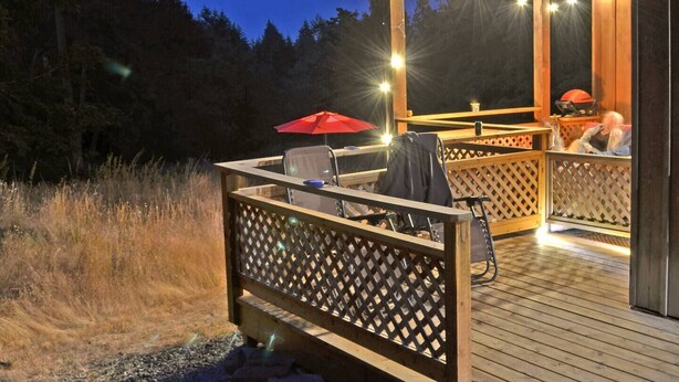 An outdoor deck with a wooden pergola, seating area, and a grill. - Welcome to the Meadowverse, your peaceful retreat (Galiano Island)