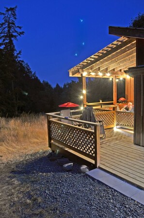 An outdoor deck with a wooden pergola, seating area, and a grill. - Welcome to the Meadowverse, your peaceful retreat (Galiano Island)