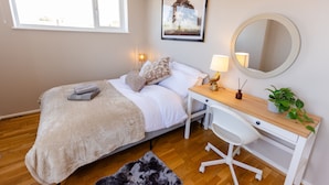 A bedroom with a bed, bedside table, desk, chair, and a large mirror. - Apartment - Sleeps 6 - Parking - Wifi (Guildford)