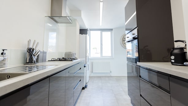 A modern kitchen with a long countertop, stainless steel appliances, and a window providing natural light. - Apartment - Sleeps 6 - Parking - Wifi (Guildford)