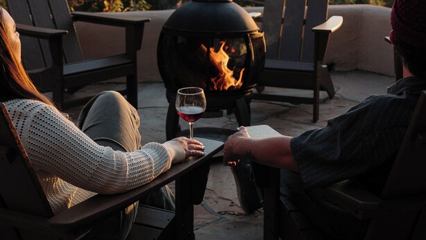 Two people seated at a table with a wood-burning stove, overlooking a scenic landscape. - Salto Retreat, Valley Views, HotTub, Patio, Hiking (Arroyo Seco)