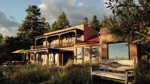 A two-story building with a balcony, large windows, and a wooden bench in front. - Salto Retreat, Valley Views, HotTub, Patio, Hiking (Arroyo Seco)