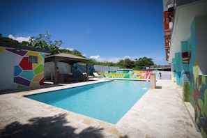 Una piscina al aire libre, sombrillas, sillones reclinables de piscina