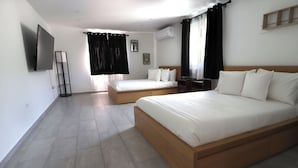 A hotel room with two beds, a TV, and a standing fan. - Oceanview Apartment with Rooftop (Terranova)