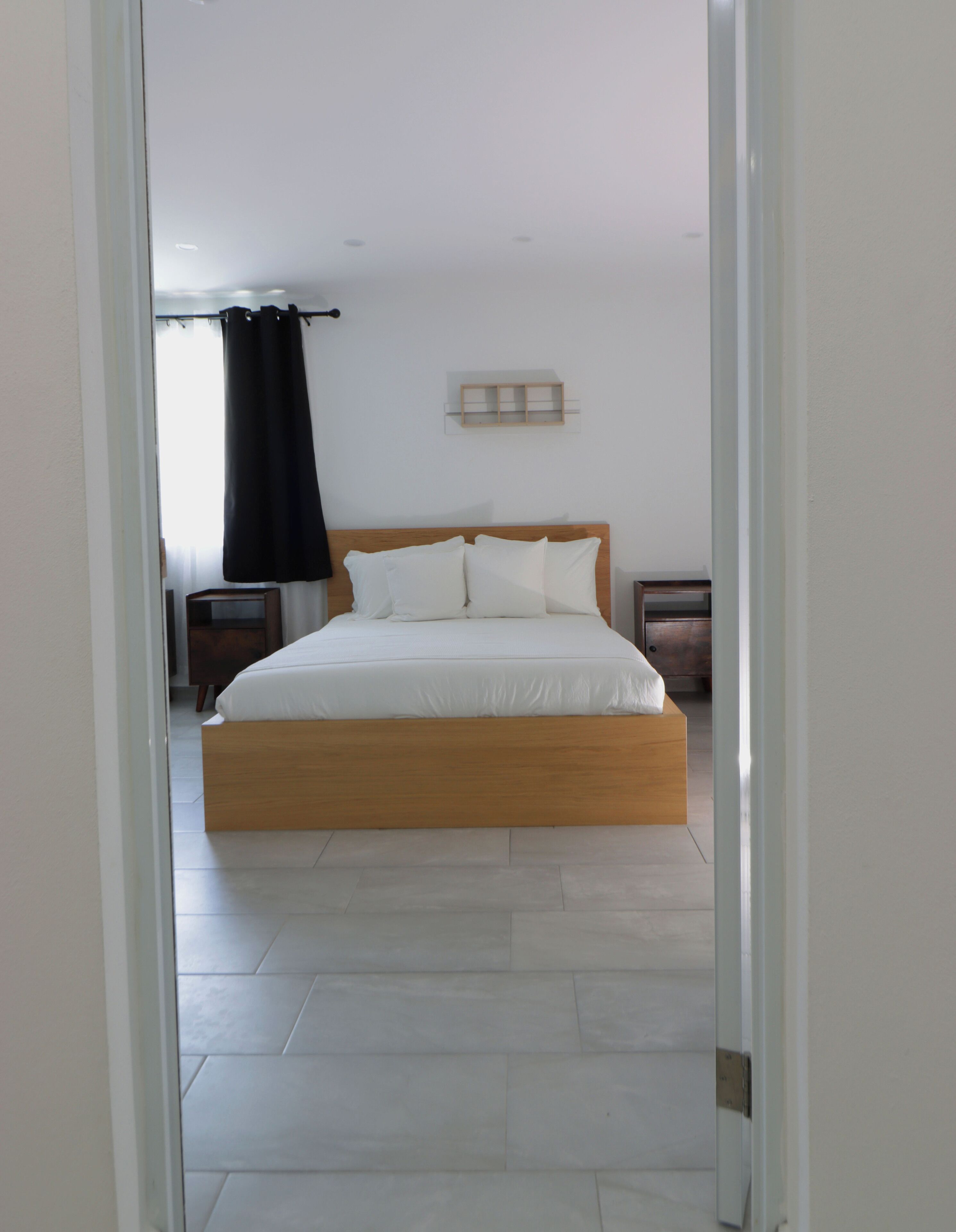 Een slaapkamer met een houten bed, wit beddengoed, een nachtkastje en een bedtafel.