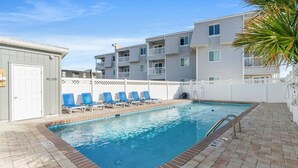 Ein Pool mit Liegestühlen, einer Pflasterterrasse und einem weißen Zaun.
