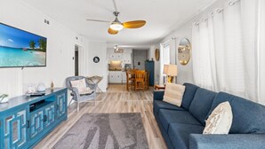 Ein Wohnzimmer mit einem blauen Sofa, einem Fernseher und einem Deckenventilator.