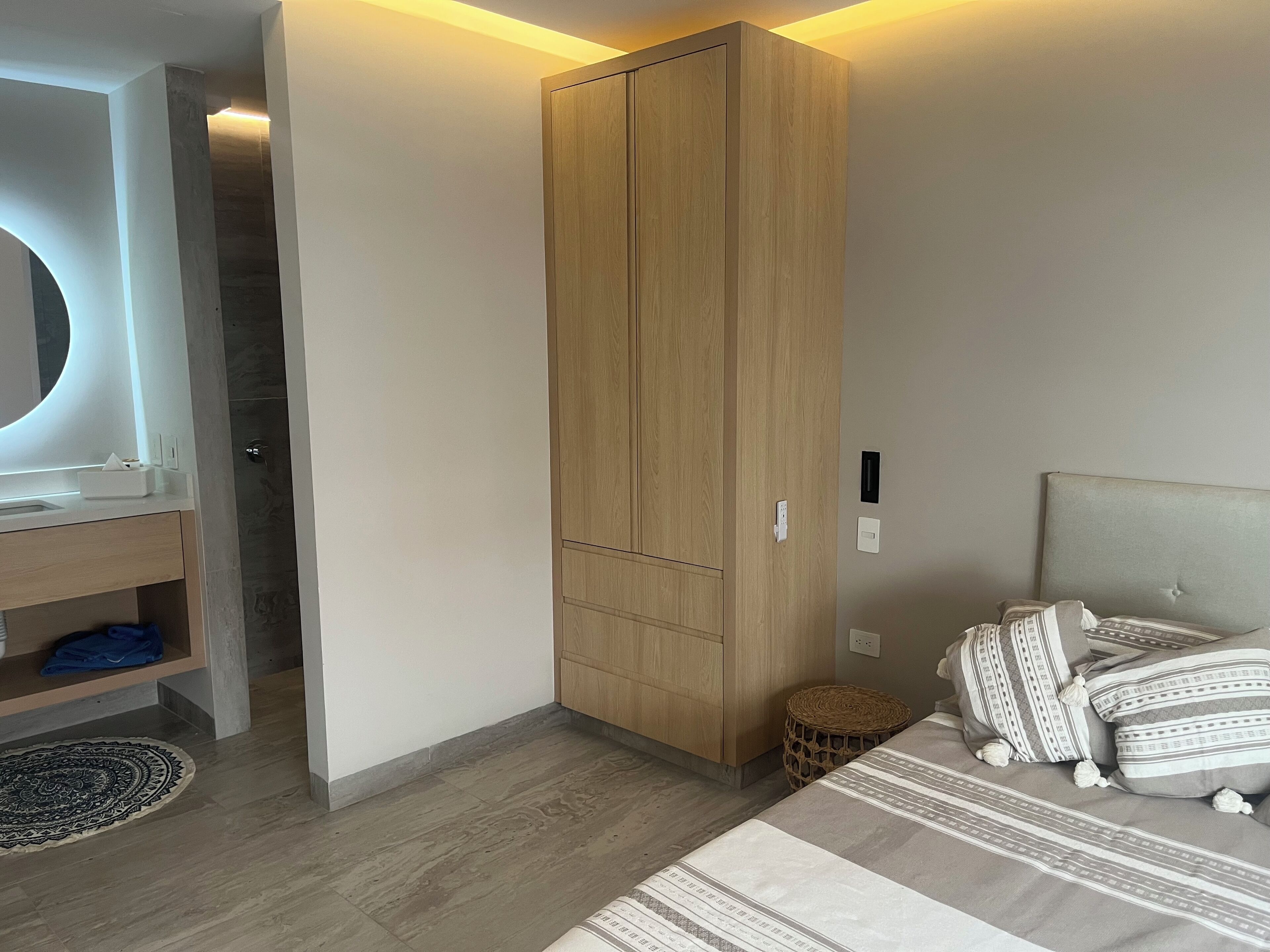 A bedroom with a bed, a wardrobe, a bedside table, and a mirror.