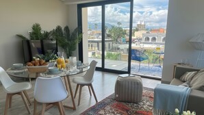 Un salon moderne comprenant un coin repas, de grandes fenêtres offrant une vue sur la ville et un espace salon confortable.