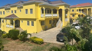A large yellow building with multiple balconies and a central staircase. - Kingsbird by the sea Inn  (Discovery Bay)