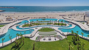 Een resort met meerdere zwembaden, een strand en uitzicht op de oceaan.