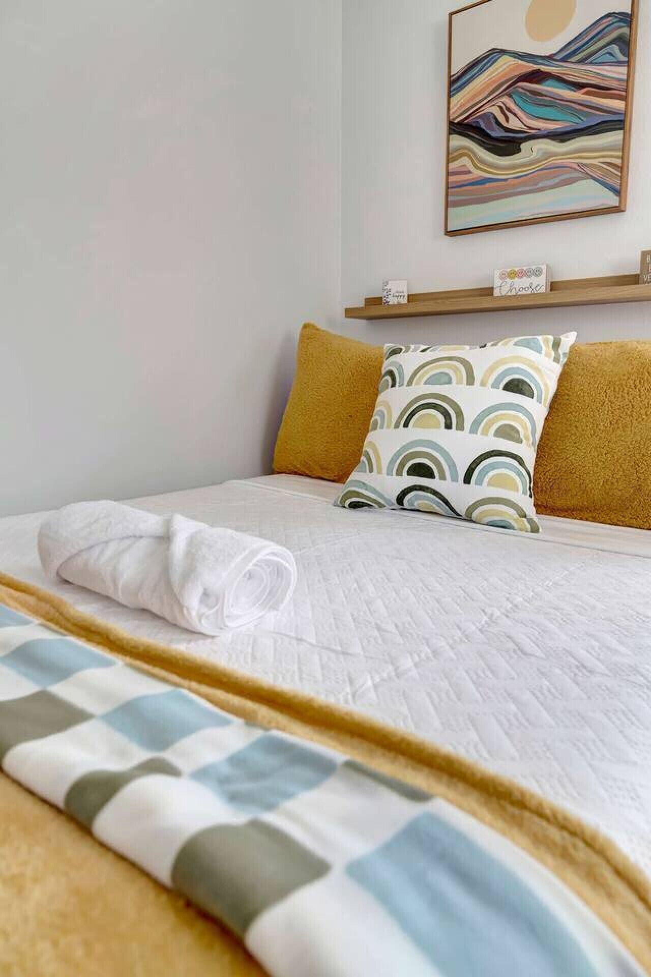 A neatly made bed with a white duvet, two pillows, and a decorative throw.