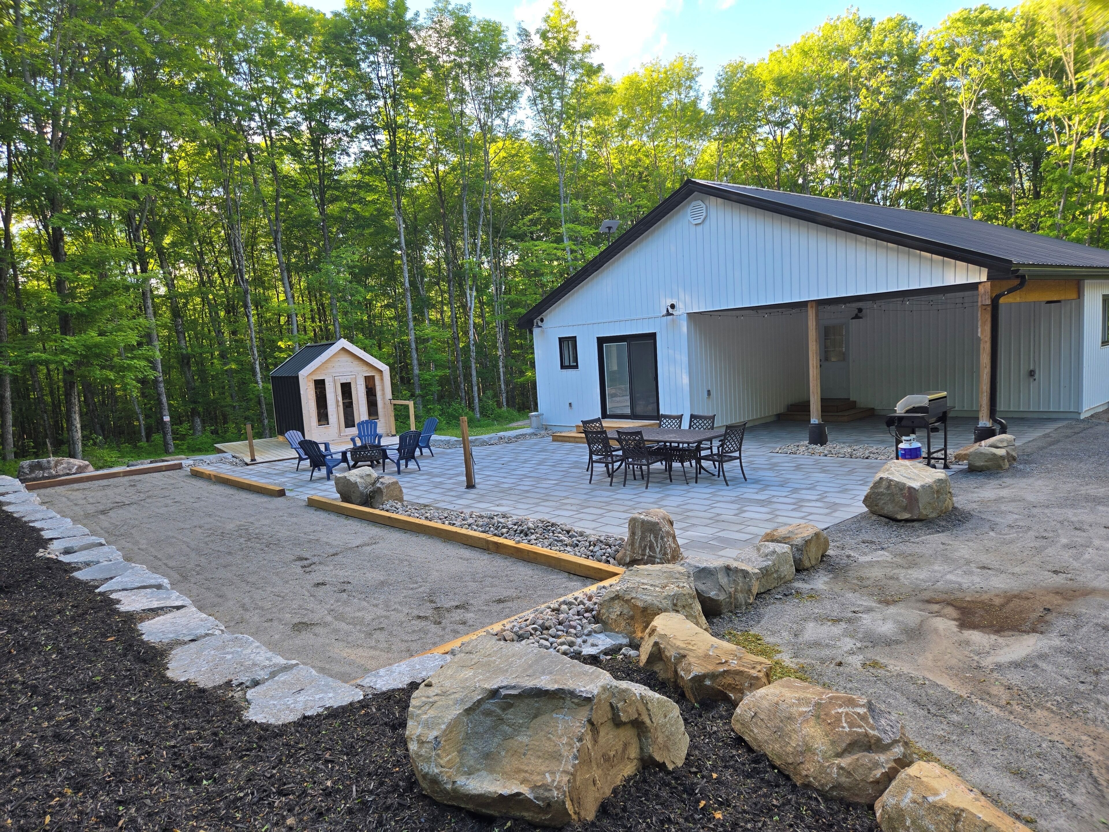 A building with a covered patio area, a small wooden structure, and outdoor seating.