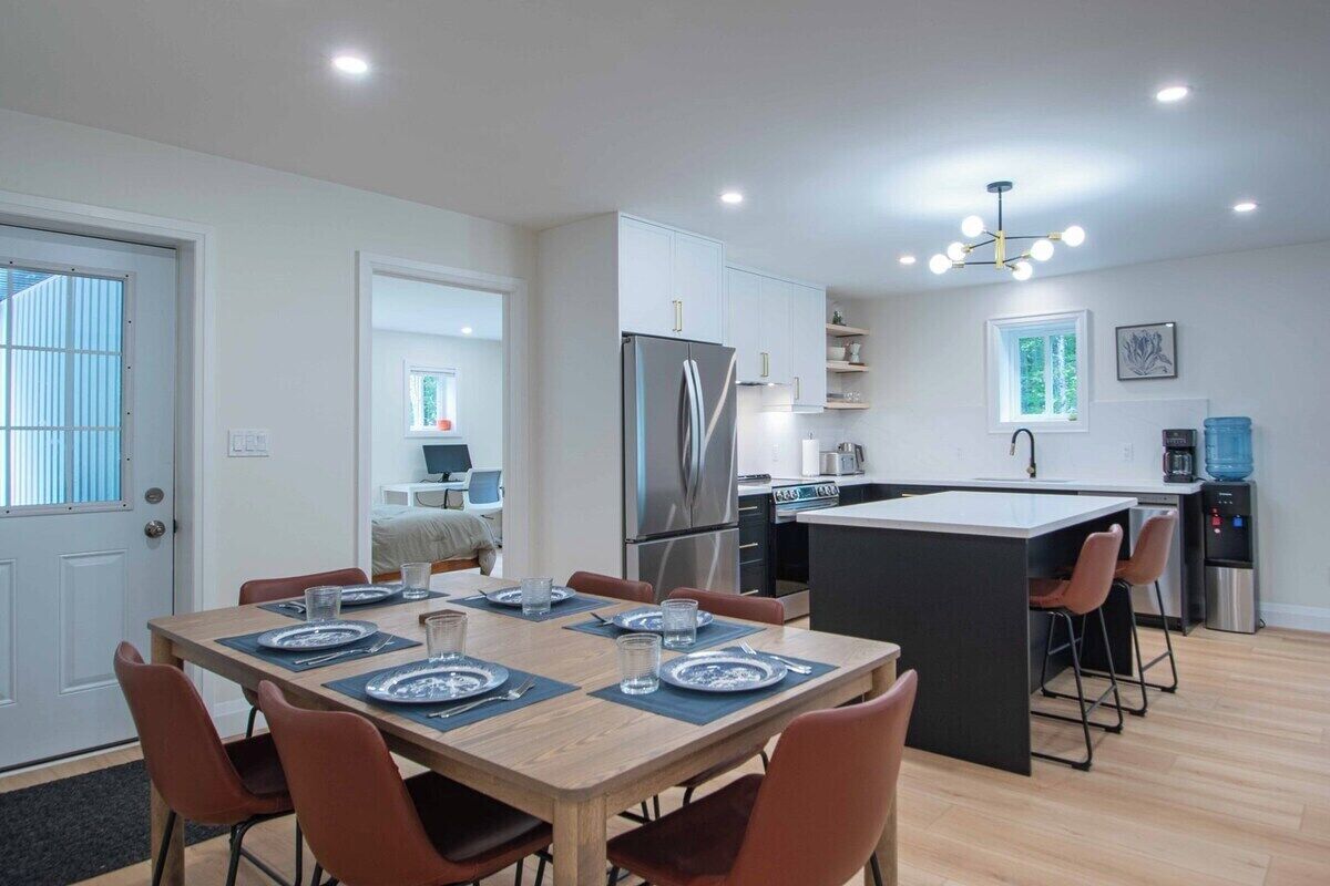 Una cocina moderna con una isla central, mesa de comedor con sillas y un refrigerador.