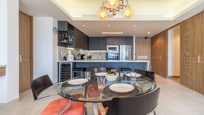 Una cocina moderna con una isla central, electrodomésticos integrados y un comedor con mesa y sillas de vidrio.