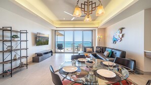 Una sala de estar moderna con una mesa de comedor de vidrio, un sofá y un televisor montado en la pared.