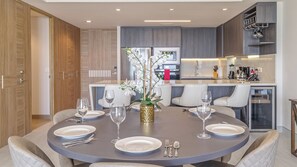 A modern dining area with a round table set for four, surrounded by white upholstered chairs.