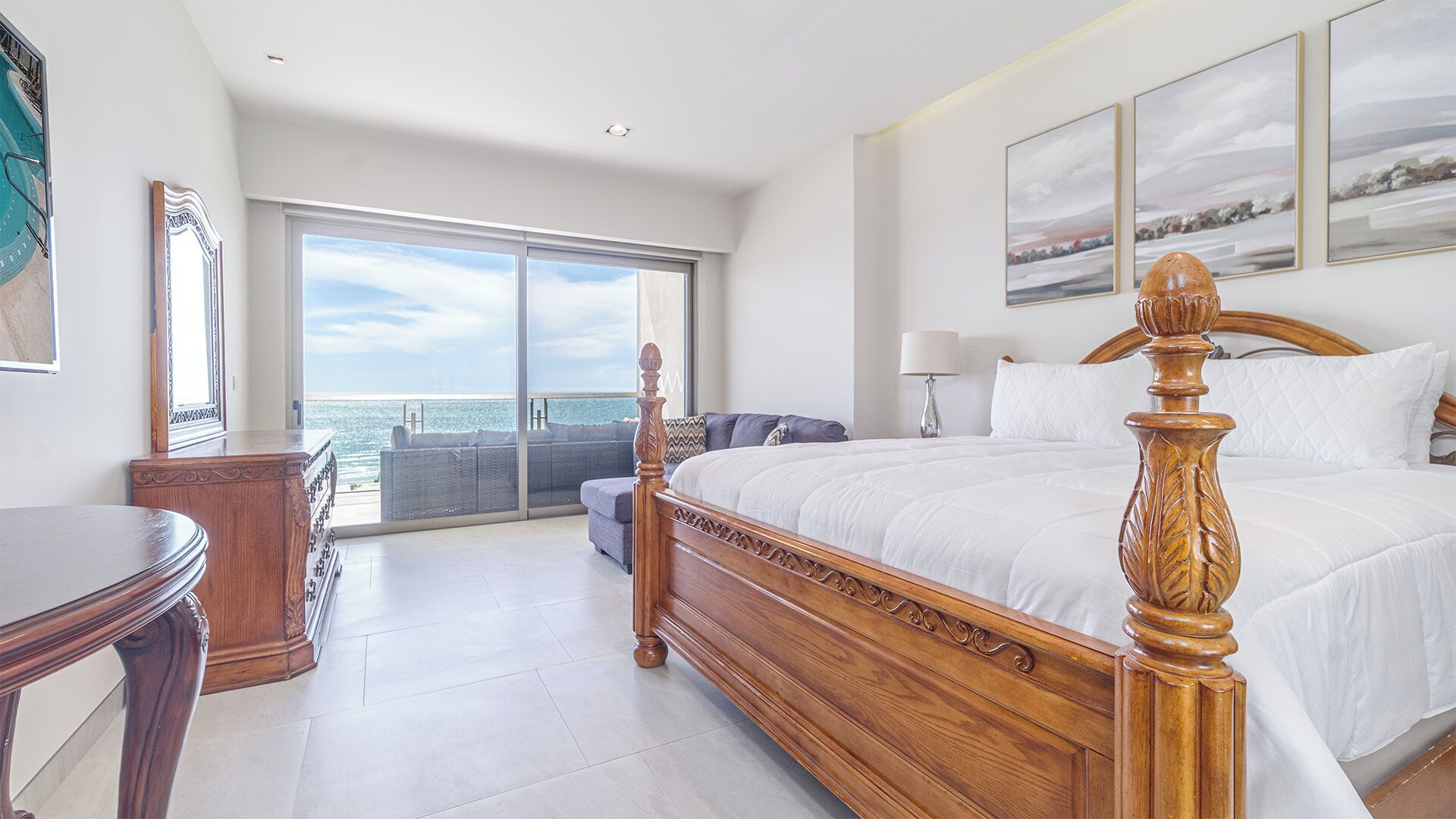 Ein geräumiges Schlafzimmer mit einem großen Bett, Meerblick durch eine Schiebetür und einem Balkon.