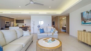 Een moderne woonkamer met een bank, salontafel en een eethoek op de achtergrond.