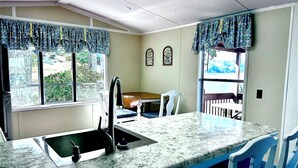 A kitchen with a granite countertop, a sink, and a dining area with a table and chairs.