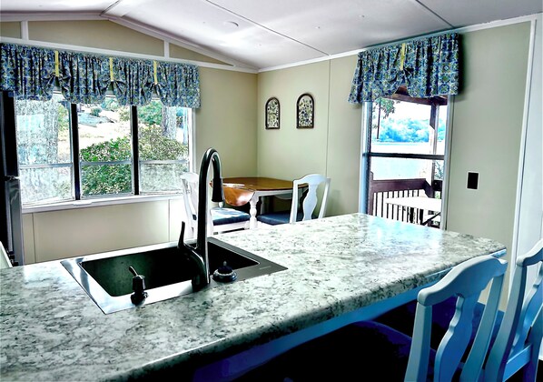 Una cocina con encimera de granito, un lavamanos y una zona de comedor con una mesa y sillas.