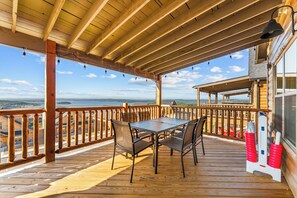 A wooden deck with a table and chairs, overlooking a body of water and distant land. - Table Rock View Log Cabin with Private Hot Tub, Firepit, Lake Access & Free Attraction Tickets (Branson)