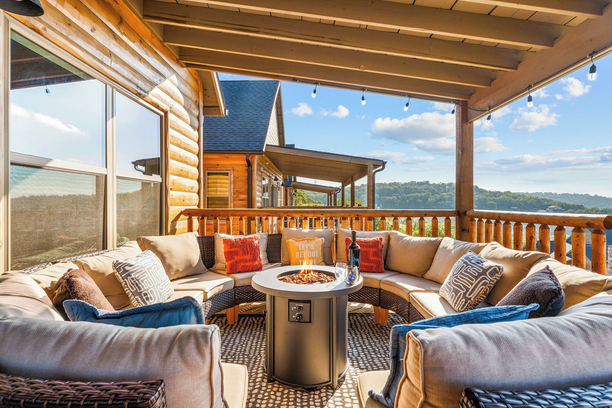 A cozy outdoor seating area with a fire pit, wooden furniture, and a view of a mountain landscape.