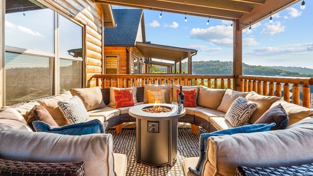 Un rincón exterior acogedor con una chimenea, mobiliario de mimbre y vistas a una cabaña de madera.