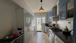 Cozinha moderna com fogão, forno e máquina de lavar louça. Há uma janela com vista para o exterior.