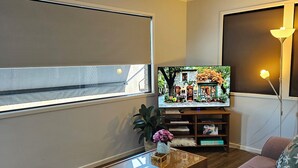Een woonkamer met een bank, een salontafel, een televisie en een lamp.
