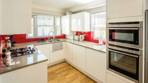Une cuisine moderne avec des armoires blanches, une cuisinière en acier inoxydable et un four encastré.