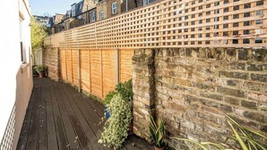 Une terrasse en bois avec un mur en briques et une clôture en treillis de bois.