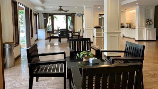 A spacious hotel lobby with a dining area, a kitchen in the background, and large windows allowing natural light. - Suansin Lanna Hotel (Tak)