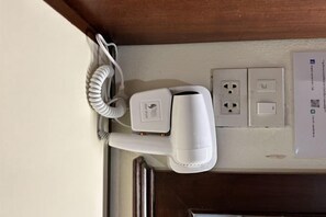 A hair dryer and a power outlet on a wall. - Suansin Lanna Hotel (Tak)