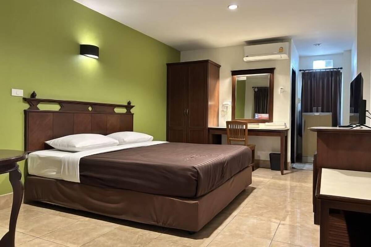 A hotel room with a large bed, a desk, a wardrobe, and a mirror.