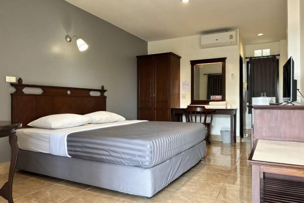 A hotel room with a bed, a desk, a mirror, and a wardrobe.