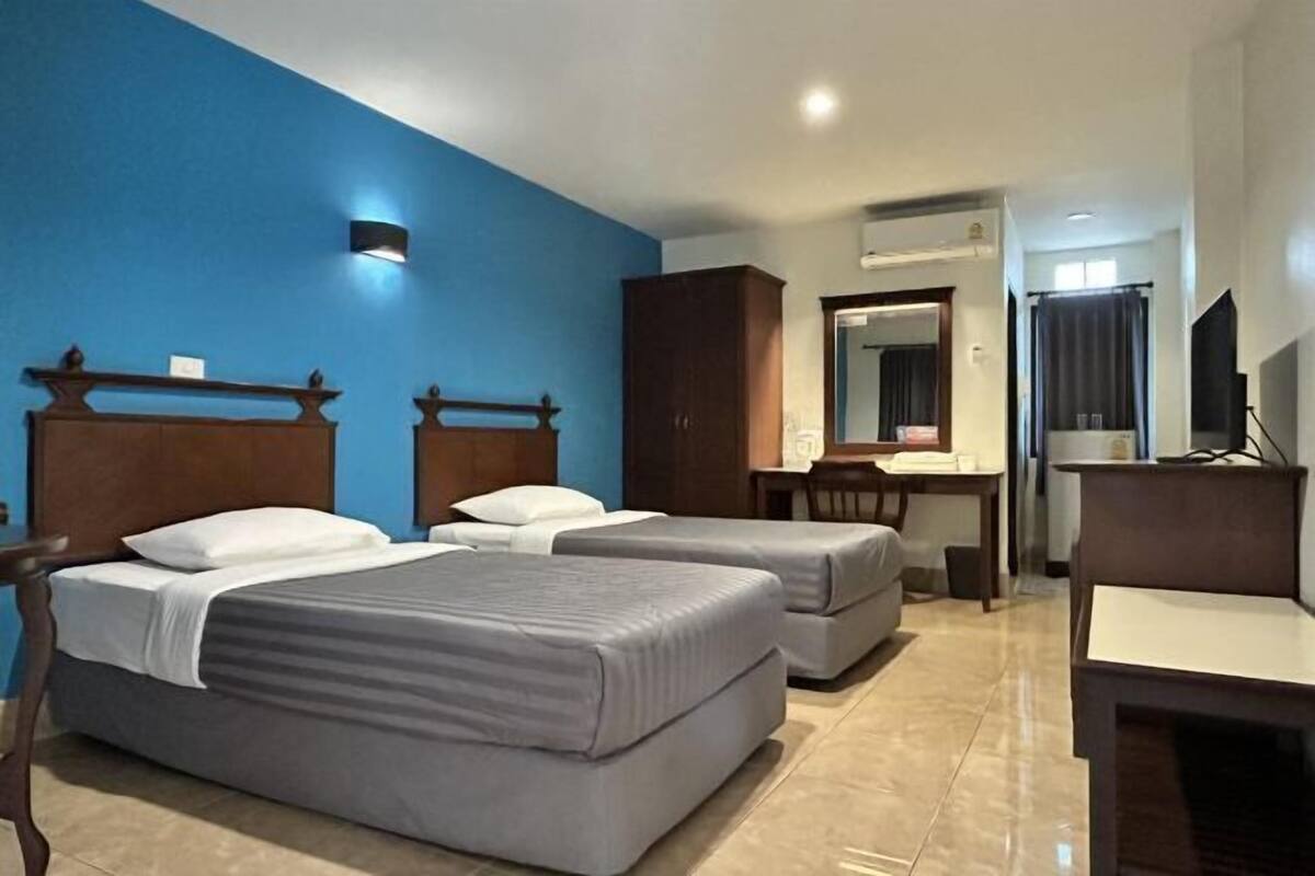 A hotel room with two beds, a desk, a chair, and a mirror.