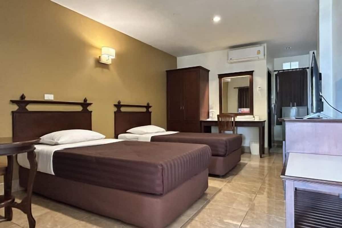 A hotel room with two beds, a desk, a mirror, and a television.