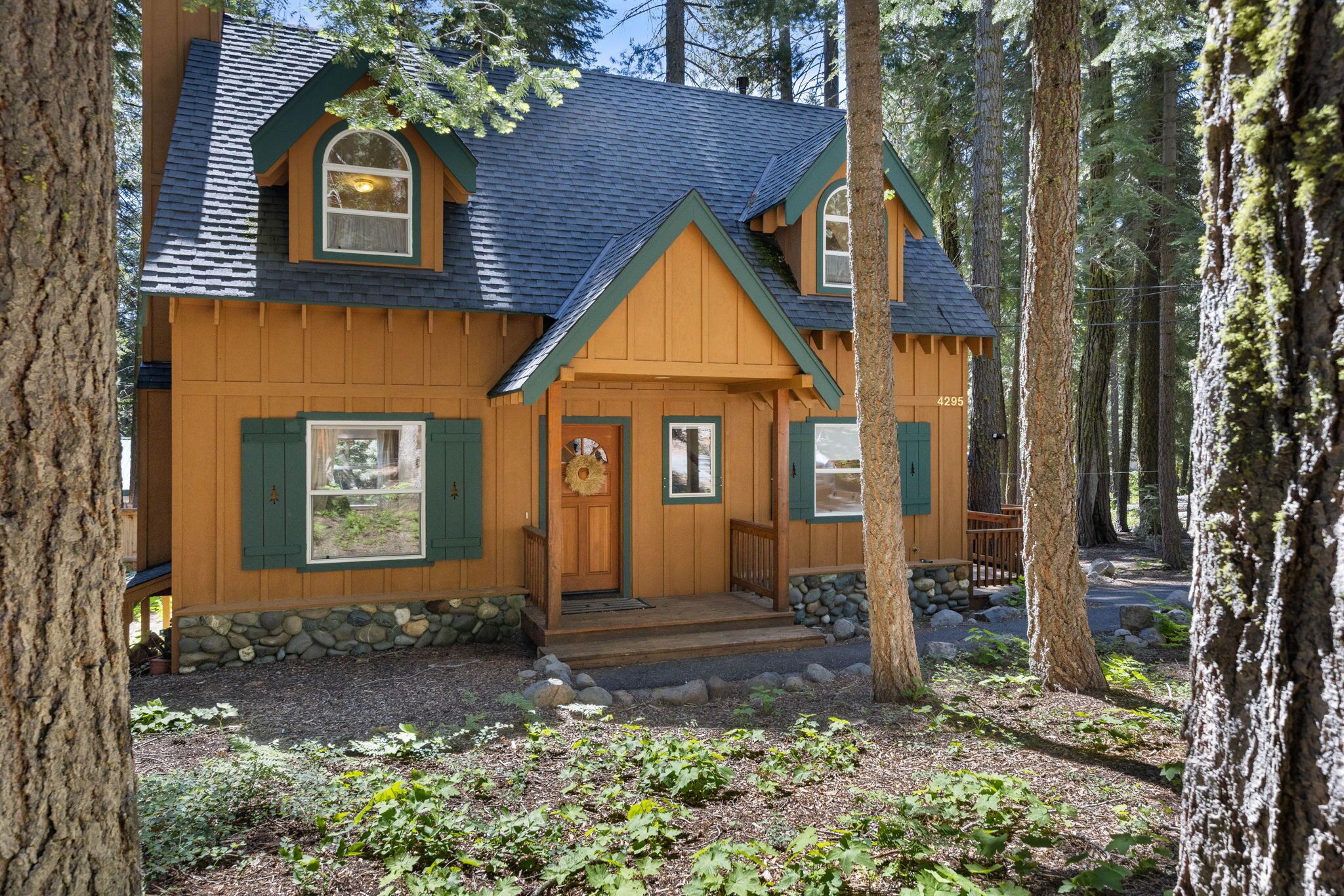 A cabin with a stone foundation, a porch, and a chimney.