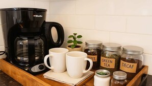 A coffee maker, two white mugs, a small plant, and jars labeled 'GREEN TEA' and 'DECAF' on a wooden tray. - Sleeps 5  Peaceful  King Bd  Walk Score 98 (Philadelphia)