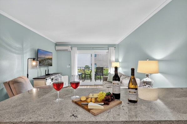 A dining area with a table set for a meal, including cheese, grapes, and a bottle of wine.