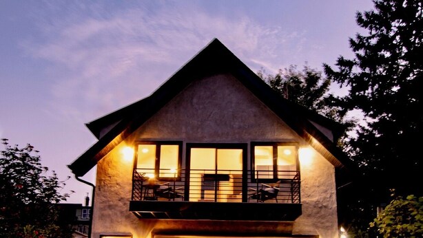 Een tweelaags huis met een garage, een balkon op de bovenverdieping en een trap naar de ingang.