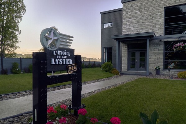 A modern building with a sign indicating 'L'ETOILE DU LAC LYSTER' and a B&B logo. - L'étoile du lac Lyster (Coaticook)