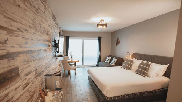 A modern hotel room with a large bed, a desk, and a view of the outdoors. - L'étoile du lac Lyster (Coaticook)