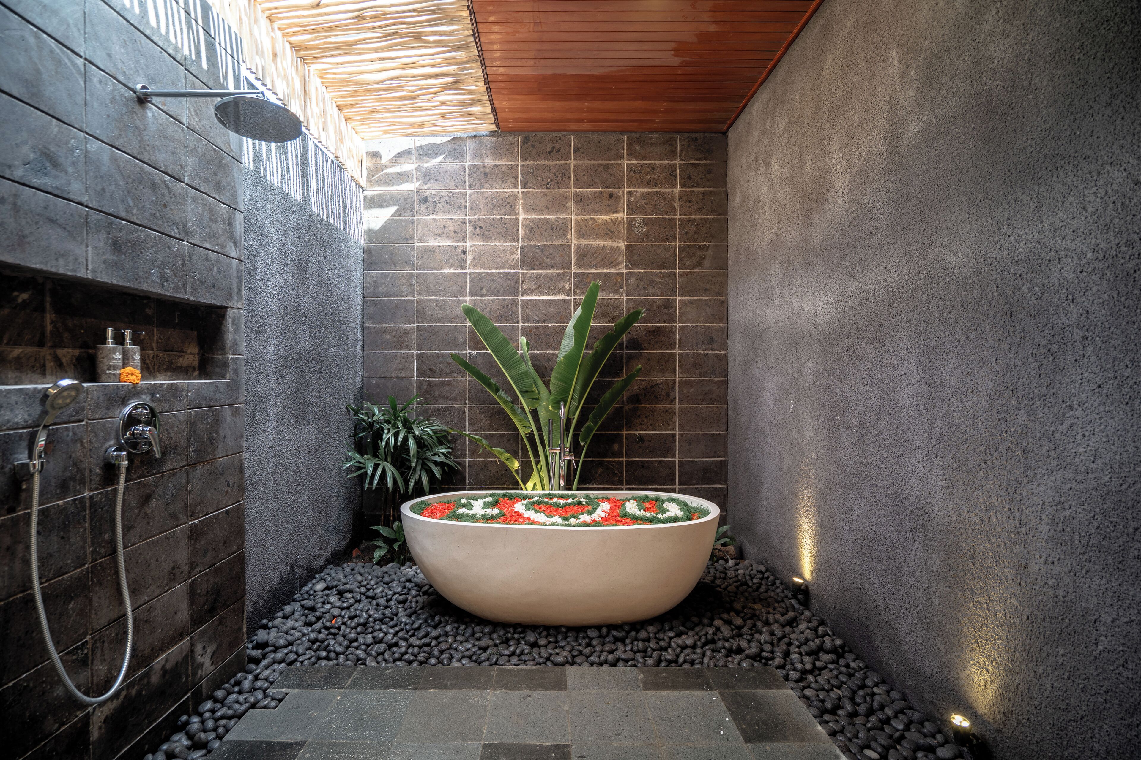 A bathroom with a large bathtub, a shower, and a potted plant.