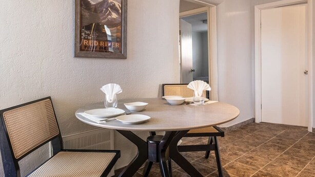 Un coin repas avec une table ronde, des chaises et un tableau encadré accroché au mur.
