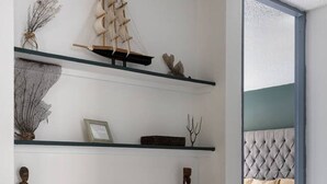 A modern interior with a minimalist design, featuring a series of floating shelves with decorative items and a framed sign.