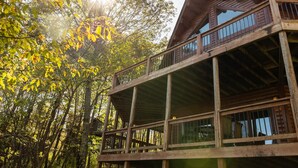 A multi-story wooden cabin with a balcony, surrounded by trees. - Splash Mountain 6 bedrooms with indoor pool & mountain and filtered lake view (Garrett County)